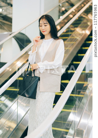 A woman riding an escalator A woman riding an escalator 117765963