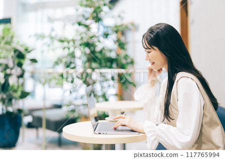 A woman using a computer in a cafe 117765994