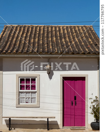 Charming Rural House with Vibrant Pink Door and Bench 117766795