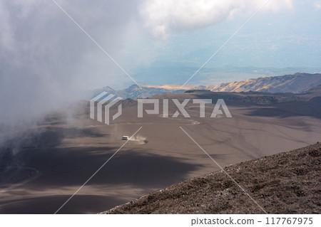A car driving through a desolate volcanic landscape 117767975
