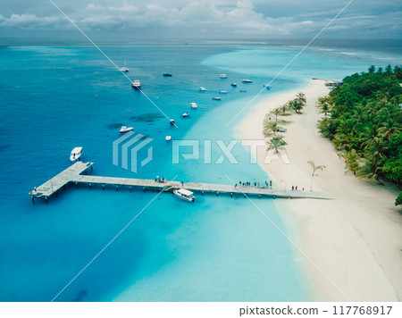Maldives beach with pier and touristic boats on Fulidhoo island. Travel vacation concept, drone shot 117768917