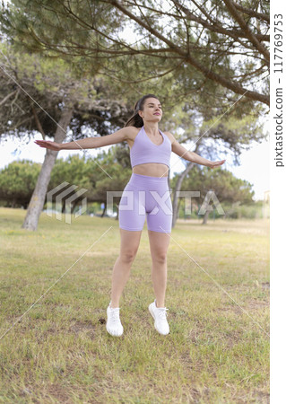 A Young Woman Is Seen Exercising Vigorously in a Peaceful Park on a Wonderfully Sunny Day 117769753