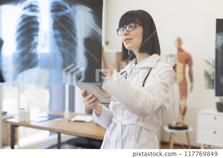 Female doctor examining chest x-rays in medical office Female doctor examining chest x-rays in medical office 117769849