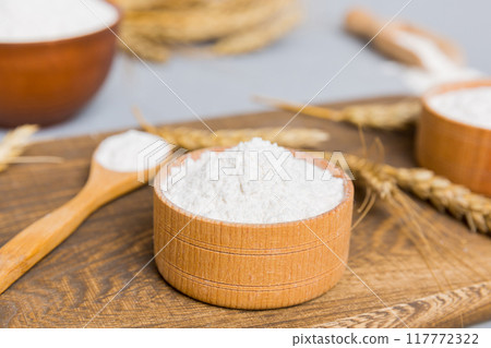 Flat lay of Wheat flour in wooden bowl with wheat spikelets on colored background. world wheat crisis 117772322