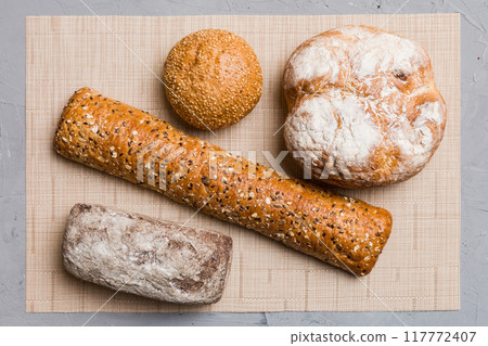 Assortment of freshly baked bread with napkin on rustic table top view. Healthy unleavened bread. French bread Assortment of freshly baked bread with napkin on rustic table top view. Healthy unleavened bread. French bread 117772407