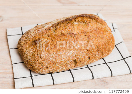 freshly baked bread with napkin on rustic table top view. Healthy white bread loaf isolated 117772409