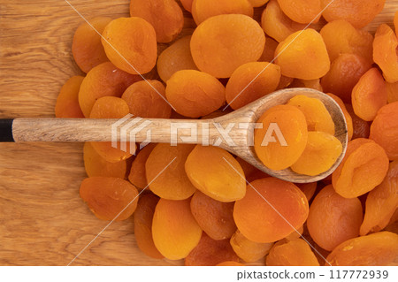 heap of dried apricots on wooden background 117772939