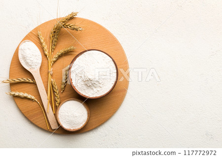 Flat lay of Wheat flour in wooden bowl with wheat spikelets on colored background. world wheat crisis 117772972