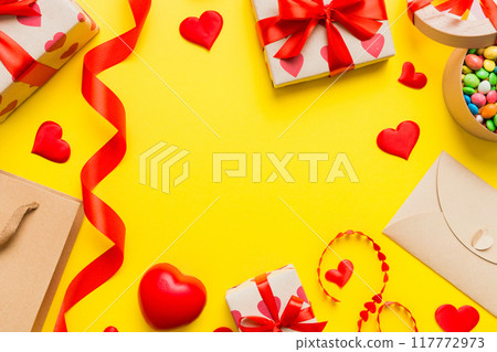 top view photo of st valentine day decor shopping, bag, envelope, gift, box, candy and red heart on colored background with empty space. Frame background 117772973