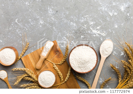 Flat lay of Wheat flour in wooden bowl with wheat spikelets on colored background. world wheat crisis 117772974