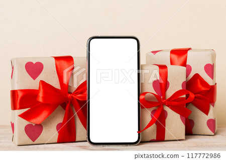 mobile phone with blank screen on colored background with hearts, calendar and gift box, valentine day concept perspertive view flat lay mobile phone with blank screen on colored background with hearts, calendar and gift box, valentine day concept perspertive view flat lay 117772986