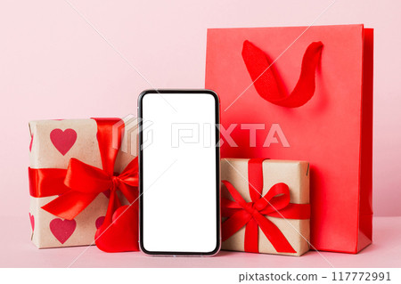 mobile phone with blank screen on colored background with hearts, calendar and gift box, valentine day concept perspertive view flat lay mobile phone with blank screen on colored background with hearts, calendar and gift box, valentine day concept perspertive view flat lay 117772991
