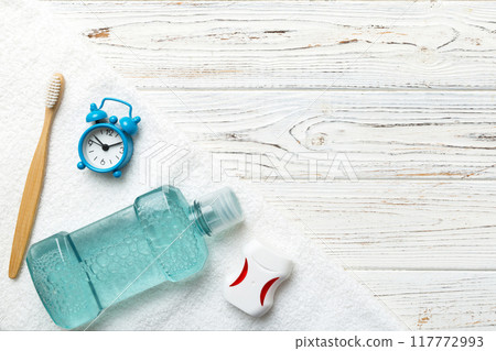 Mouthwash and other oral hygiene products on colored table top view with copy space. Flat lay. Dental hygiene. Oral care products and space for text on light background. concept Mouthwash and other oral hygiene products on colored table top view with copy space. Flat lay. Dental hygiene. Oral care products and space for text on light background. concept 117772993