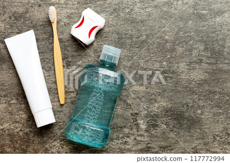 Mouthwash and other oral hygiene products on colored table top view with copy space. Flat lay. Dental hygiene. Oral care products and space for text on light background. concept Mouthwash and other oral hygiene products on colored table top view with copy space. Flat lay. Dental hygiene. Oral care products and space for text on light background. concept 117772994