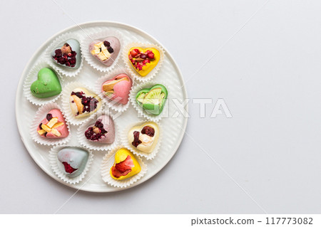 Plate with different chocolate on colored background. Assortment of fine chocolates top view vith copy space Health and obesity concept 117773082