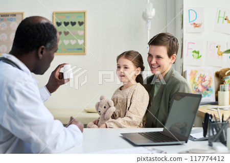 Doctor Showing Medication to Mother and Daughter in Office 117774412