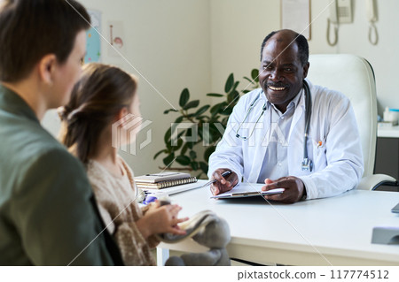 Smiling Doctor Consulting Child Patient and Guardian 117774512