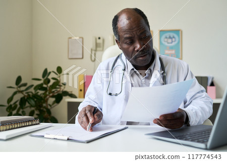 African American Doctor Reviewing Patient Documents Carefully African American Doctor Reviewing Patient Documents Carefully 117774543