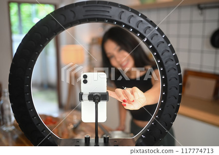 Smiling athletic young woman recording video lesson on smart phone about how to making healthy meal Smiling athletic young woman recording video lesson on smart phone about how to making healthy meal 117774713