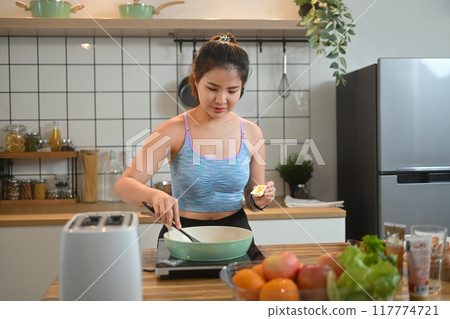 Young woman sportswear preparing healthy food for breakfast in kitchen after doing workout at home 117774721