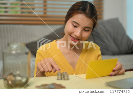 Pretty asian woman counting coins on table, managing home budget. Financial responsibility concept 117774725
