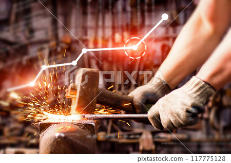 A person is hammering a piece of metal in front of a graph that shows a downward 117775128