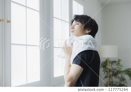 Young man in sportswear wiping sweat with a towel 117775294