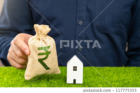 Man presents indian rupee money bag as an offer in exchange for house. Real estate appraisal. Make a deal. Housing prices. Buying a house. Man presents indian rupee money bag as an offer in exchange for house. Real estate appraisal. Make a deal. Housing prices. Buying a house. 117775355