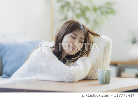A young woman in knitwear relaxing in a room A young woman in knitwear relaxing in a room 117775414