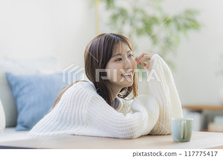 A young woman in knitwear relaxing in a room 117775417