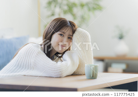 A young woman in knitwear relaxing in a room 117775425
