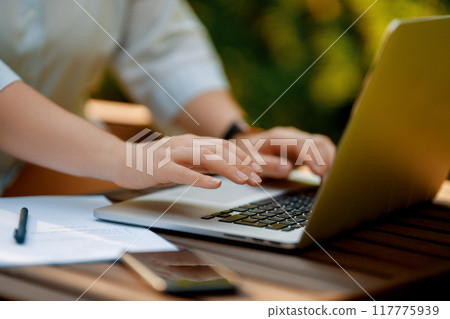 Person working on laptop in summer morning 117775939