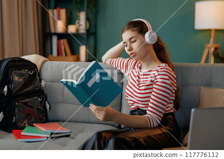 child is sitting on sofa and doing homework 117776112