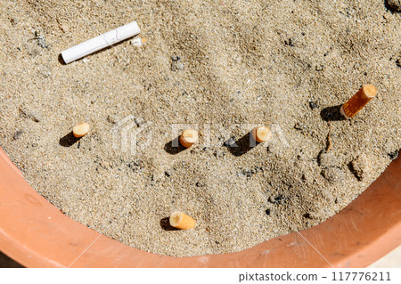 A smoking place filled with sand and cigarette butts 117776211