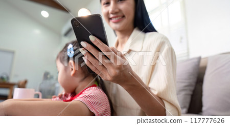 Smiling Mother Using Smartphone with Child Beside 117777626