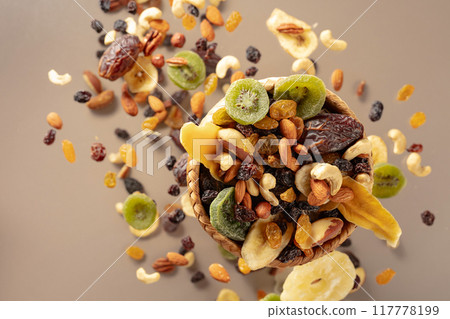 Dried tropical fruits with various nuts and raisins on a beige background. 117778199