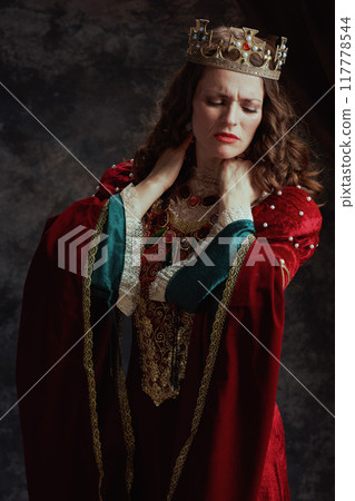 stressed medieval queen in red dress having neck pain 117778544