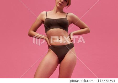 Cropped image of young woman with skinny body, slim waist posing in underwear against pink studio background 117778793