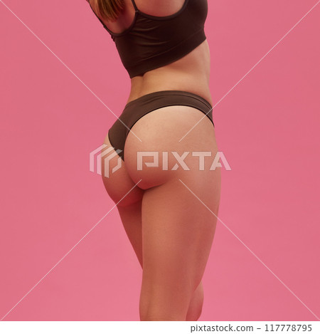 Cropped image of fit, smooth, healthy female body, buttocks in underwear against pink studio background. Anti-cellulite care 117778795