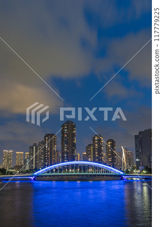 Japan: A night view of Tsukishima apartment complexes and the illuminated Eitai Bridge as seen from the Sumida River Bridge in Chuo Ward, Tokyo 117779225