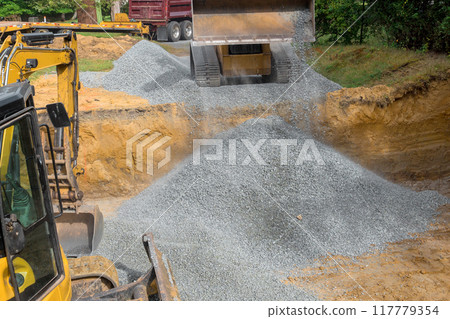 Construction site irregularities are filled with granite rubble base prior to concrete foundation being built 117779354