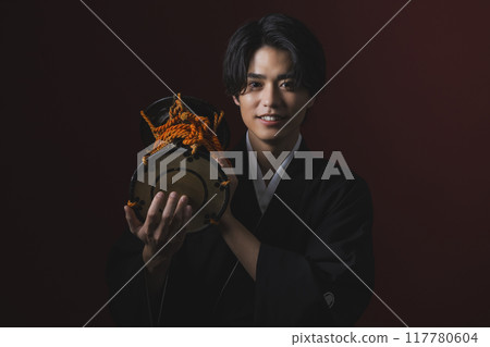 A man in a crested hakama playing a Japanese musical instrument A man in a crested hakama playing a Japanese musical instrument 117780604