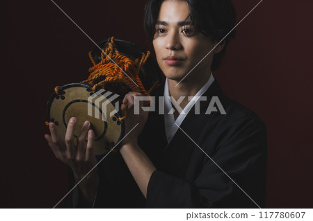 A man in a crested hakama playing a Japanese musical instrument A man in a crested hakama playing a Japanese musical instrument 117780607