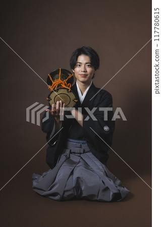 A man in a crested hakama playing a Japanese musical instrument 117780615