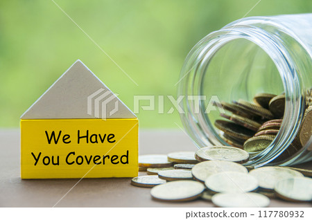Wooden toy house with text We Have You Covered with golden coins background representing protection and security. Security and insurance concept 117780932