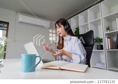 Dedicated Woman Learning Online at Home with Headphones Dedicated Woman Learning Online at Home with Headphones 117781135