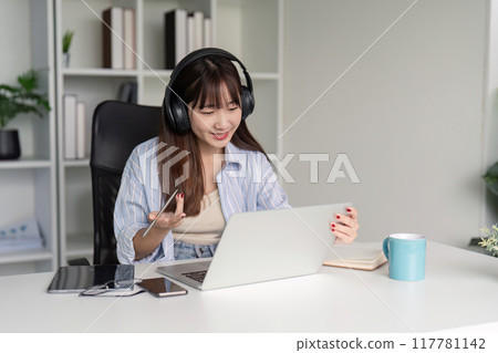 Engaged Woman Participating in Online Class with Headphones Engaged Woman Participating in Online Class with Headphones 117781142
