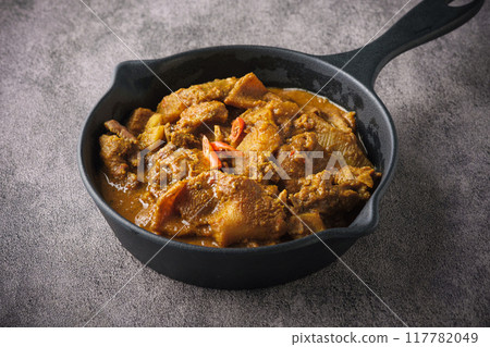 Spicy and aromatic traditional Indian goat curry served on a black pan. 117782049
