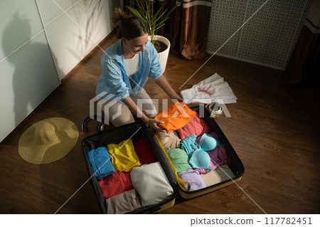 Woman organizing clothes arranging suitcase Woman organizing clothes arranging suitcase 117782451