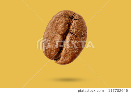 Brown coffee bean closeup isolated on yellow background Brown coffee bean closeup isolated on yellow background 117782646